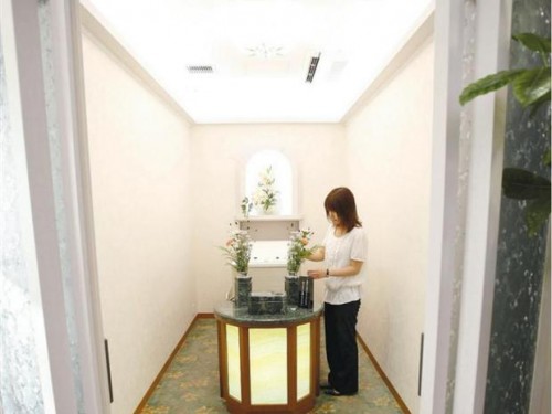 An employee adjusts flowers in a viewing room, where chilled encoffined corpses are delivered through 